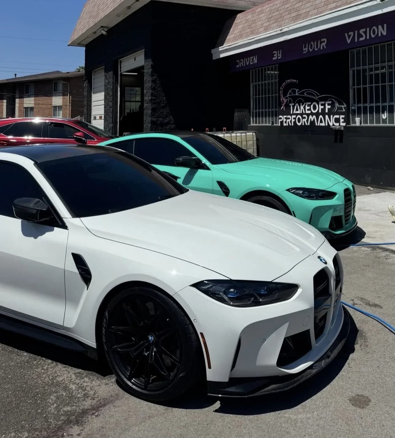 White and mint BMW M4s parked at the shop